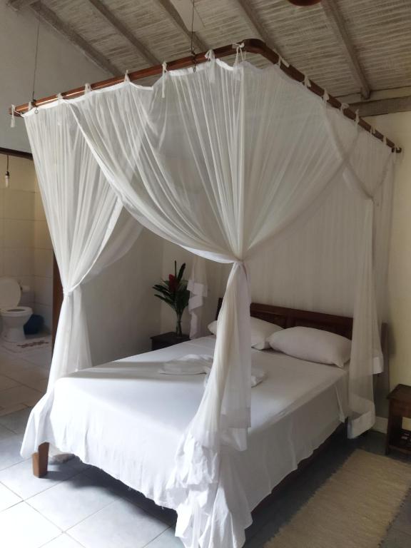 a bedroom with a white bed with mosquito netting at Casa da Drica Trancoso in Trancoso