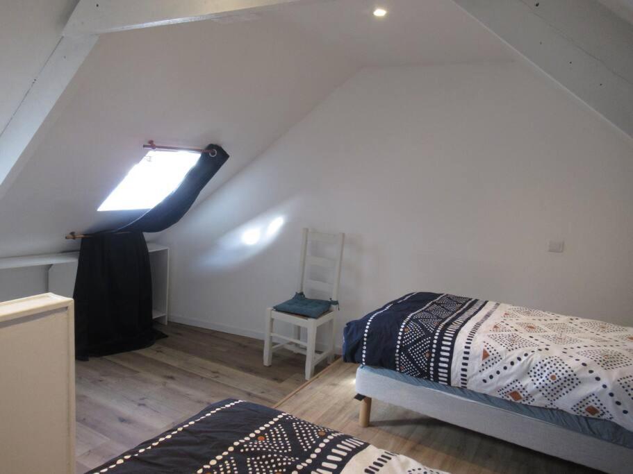 Cette chambre mansardée comprend un lit et une fenêtre. dans l'établissement Ti an traõn le petit gîte en cœur de Bretagne, à Carhaix-Plouguer