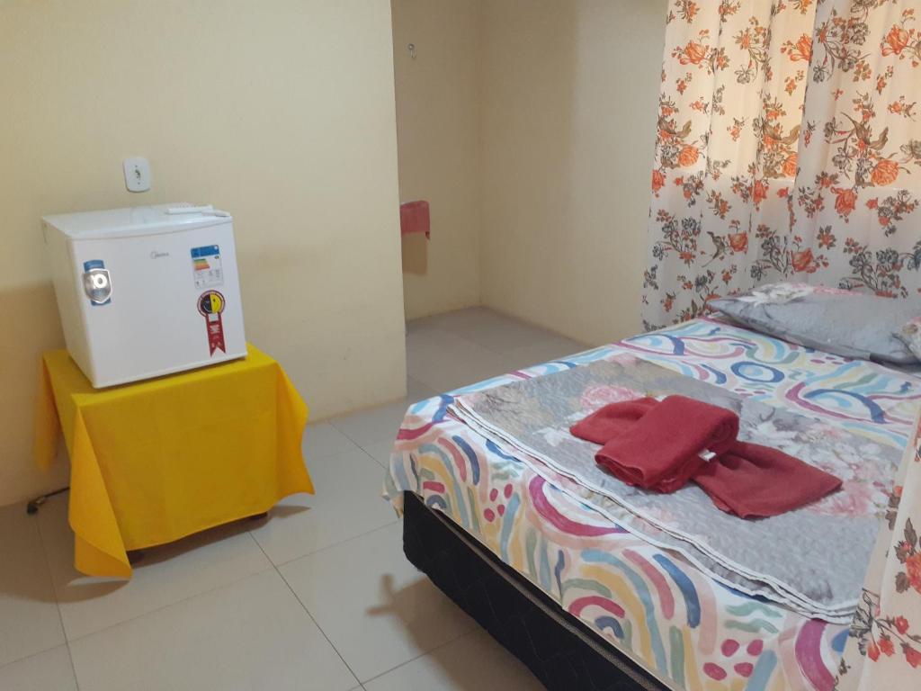 ein Schlafzimmer mit einem Bett mit einem gelben Tisch und roten Handtüchern in der Unterkunft POUSADA LUMI in Alter do Chao