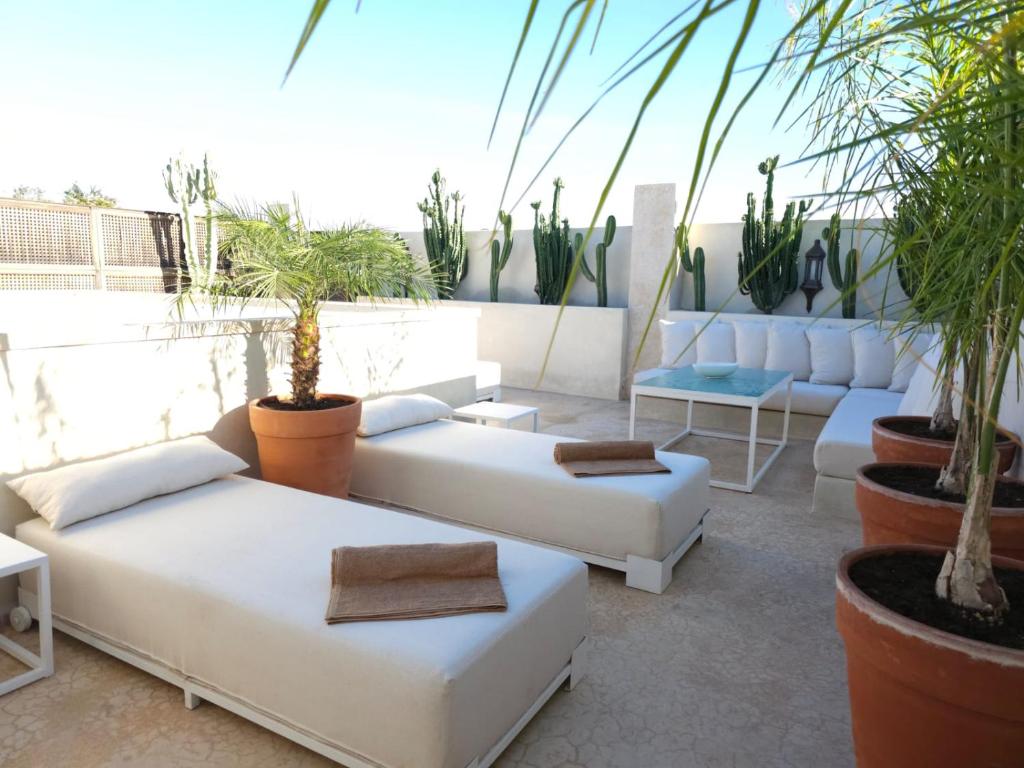 a patio with white couches and potted plants at Riad Coconut in Marrakech
