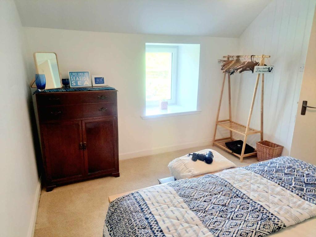 a bedroom with a bed and a dresser and a window at Cliff Cottage in Valtos