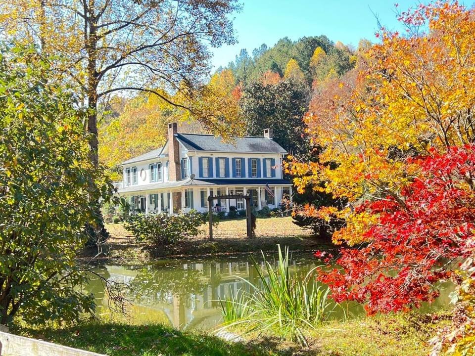 uma casa grande com um lago em frente em Historic Seaton Springs Farm B&B - James Tipton En-Suite Triple Room em Sevierville