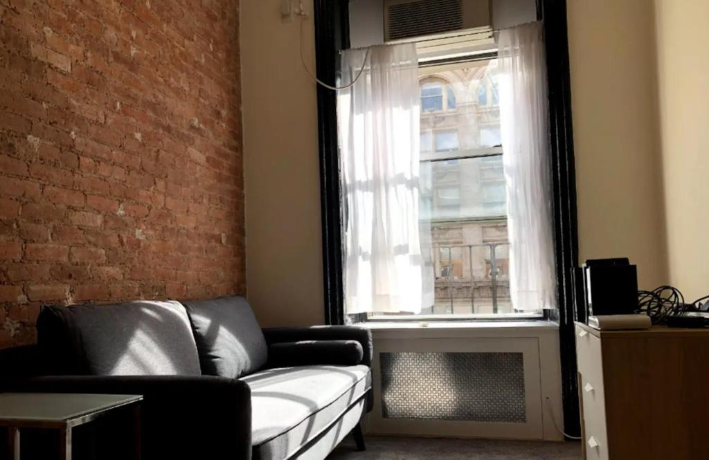 een woonkamer met een bank en een raam bij Elegant 1BR Apartment in NYC! in New York