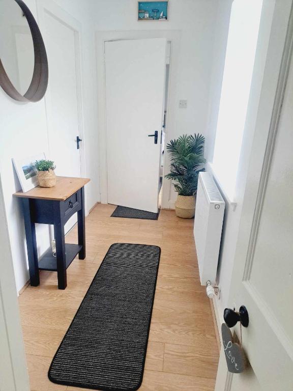 a hallway with a door and a table and a rug at Cliff Cottage in Valtos