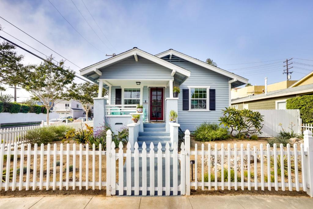 a white picket fence in front of a blue house at Huntington Beach Hideaway Near Beach and Downtown! in Huntington Beach
