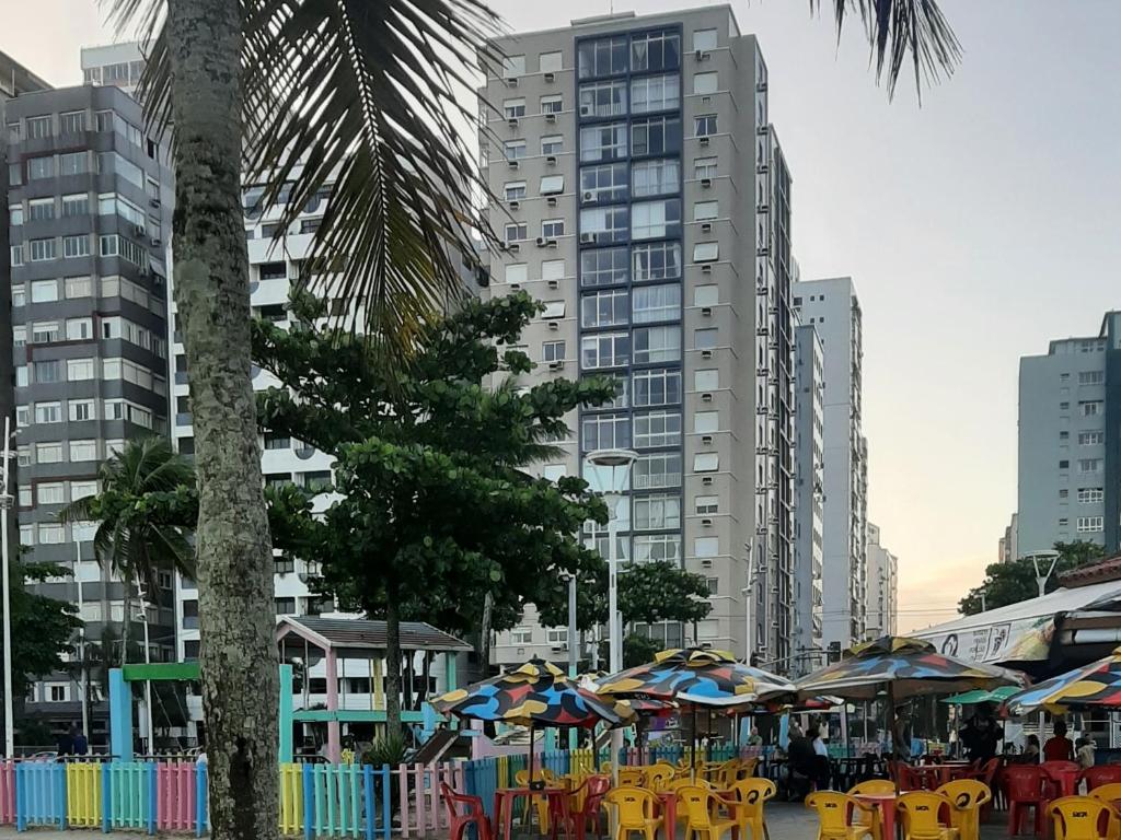 een groep tafels en stoelen met parasols in een stad bij 2 Qtos C Vista ao Mar - A 200 metros do IlhaPorchat in São Vicente