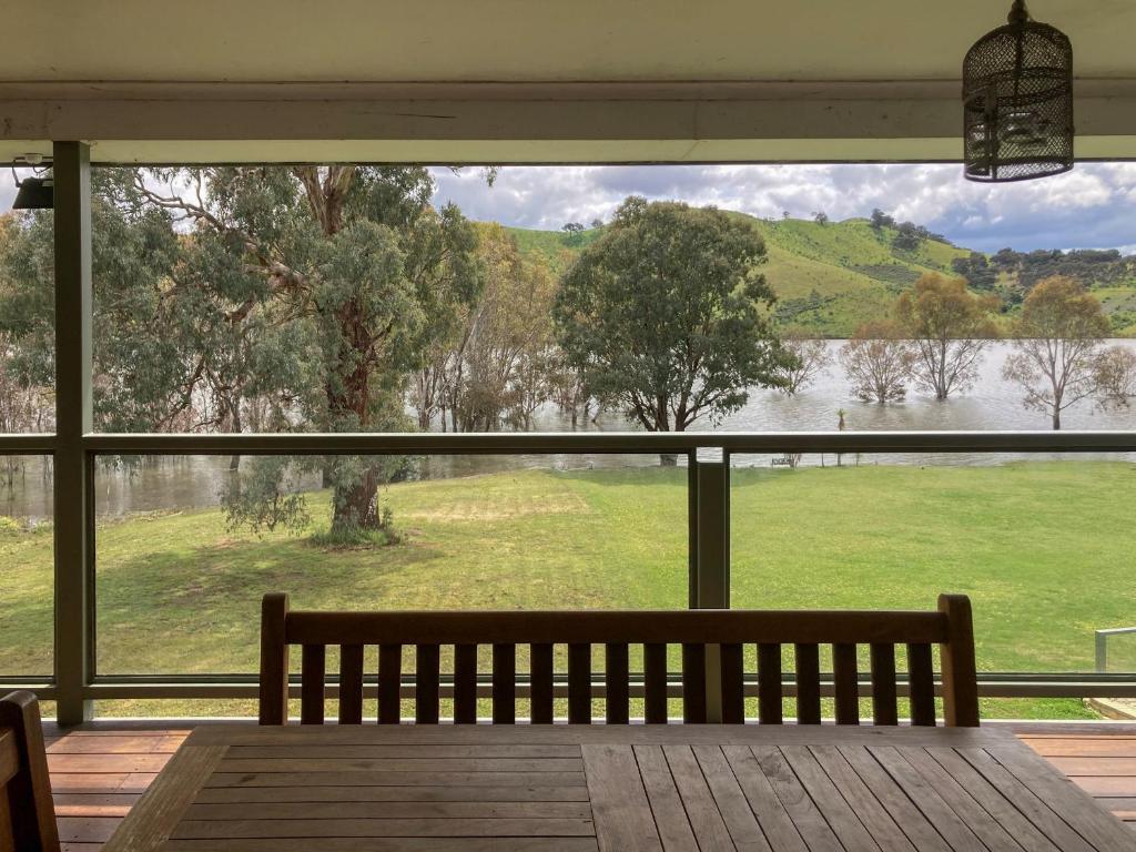 a bench sitting on a porch looking out at a lake at Eildon Views in Bonnie Doon