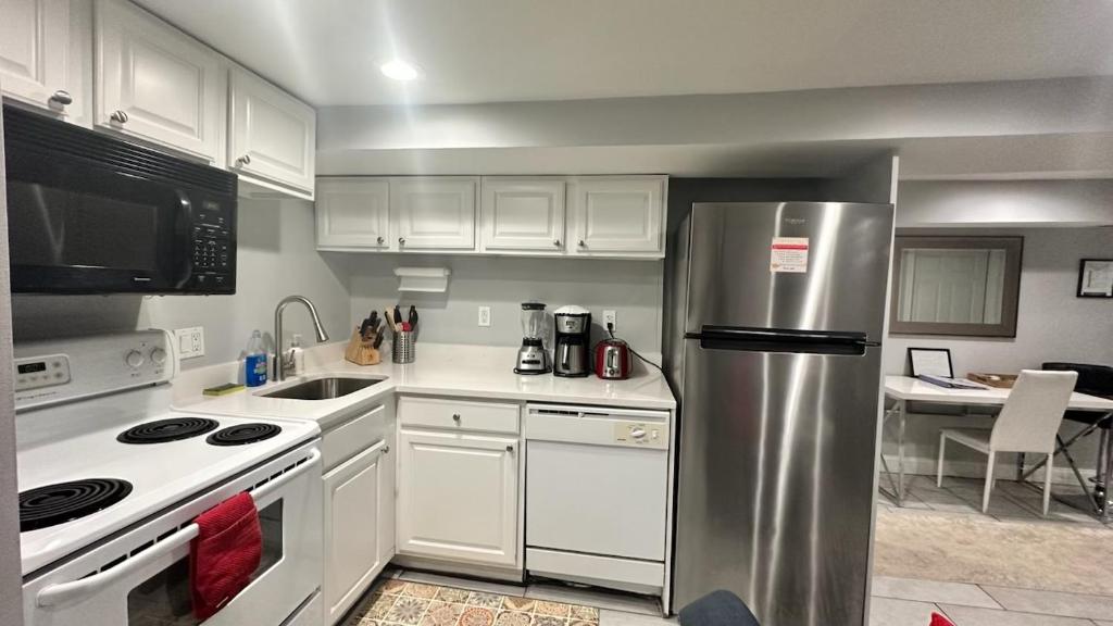 uma cozinha com armários brancos e um frigorífico de aço inoxidável em Modern Elegance Stylish Retreat Convention Center em Washington