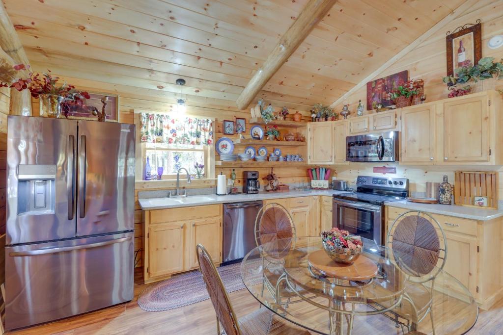 uma cozinha com uma mesa e um frigorífico de aço inoxidável em Tumbling Shoals Cabin with Fire Pit 1 Mi to Lake em Heber Springs