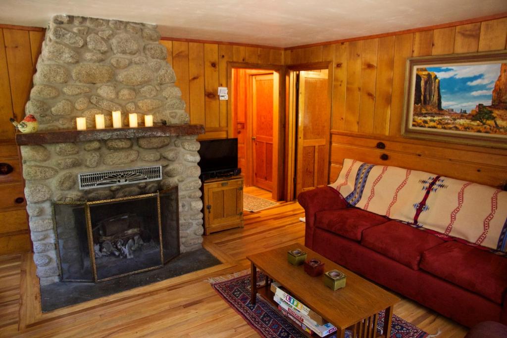 sala de estar con chimenea y sofá rojo en Ahwahnee-be Vintage Cabin - Walk to town!, en Idyllwild