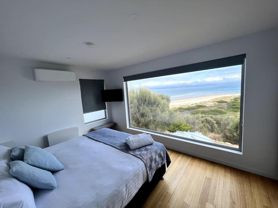 a bedroom with a large window with a large bed at Three Little Birds at Freycinet in Coles Bay