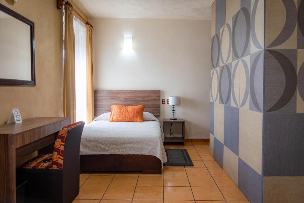 - une chambre avec un lit doté d'un oreiller orange dans l'établissement Hotel Estefania, à Morelia