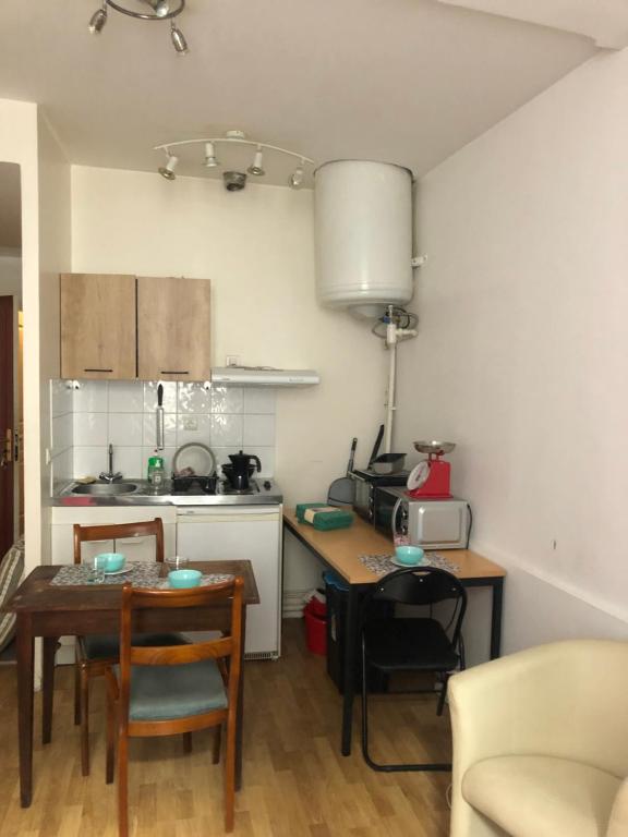 een keuken met een tafel en een kleine keuken met een fornuis bij Appartement 30m² RDC 2 pièces in Joigny