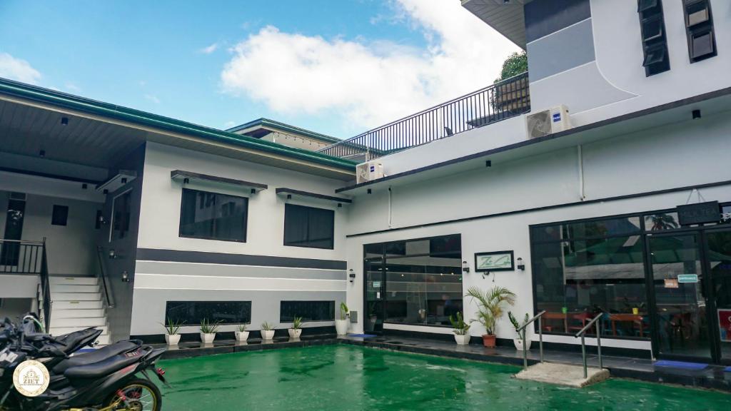 ein Haus mit einem Pool vor einem Gebäude in der Unterkunft Ziet Hotel in Mambajao
