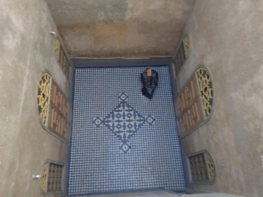 a room with a blue tile floor and a clock at Hostel riad Dar lala sofia in Fez