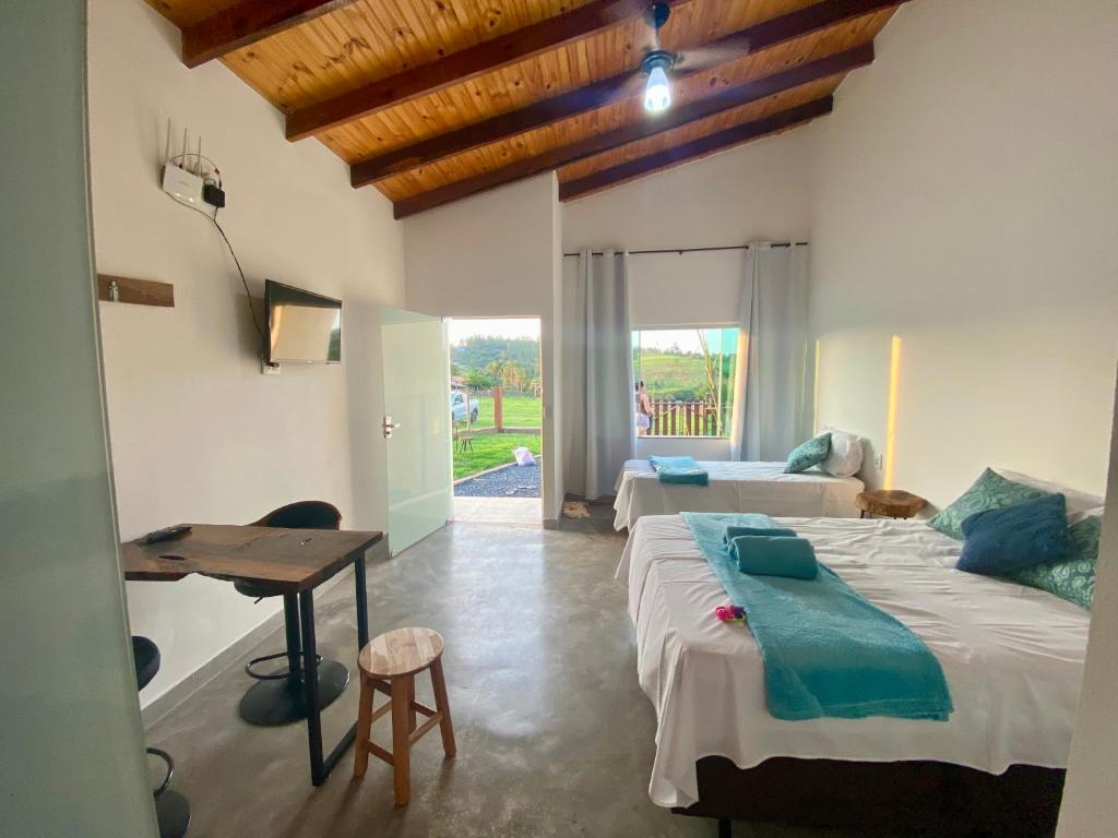 a bedroom with two beds and a table and a desk at Chalé Escarpas in Capitólio