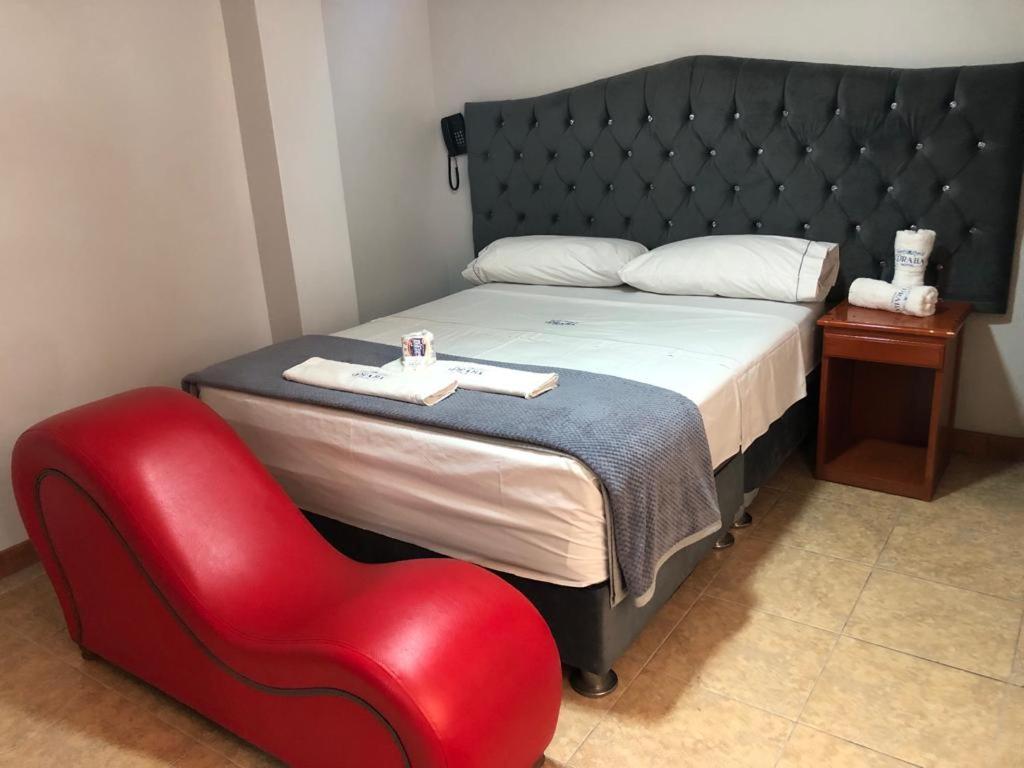 1 dormitorio con 1 cama y 1 silla roja en Hostal DRABA, en Lima