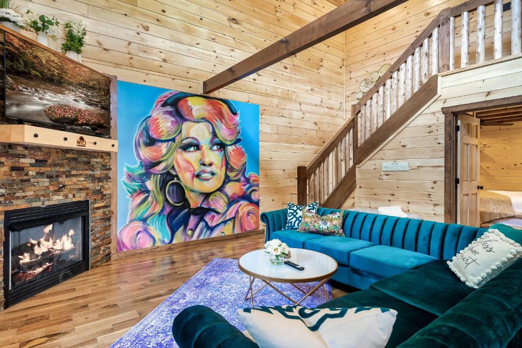 SmokiesBoutiqueCabins would love to host you at Dolly's Cute Cabin! 4 Suites with Private Bathrooms - Hot Tub, Fire Pit, Game Room, Resort Pool open Memorial Day through Labor Day! في غاتلينبرغ: غرفة معيشة بها أريكة زرقاء و لوحة
