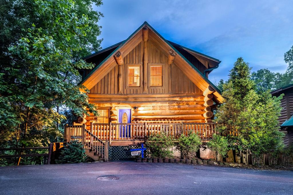 a log cabin house with a front porch and a gate at SmokiesBoutiqueCabins would love to host you! 4 miles to Gatlinburg Strip! Resort Pool open May 1 through Oct 1! Views, Shuffleboard, Hot Tub, Arcade! in Gatlinburg