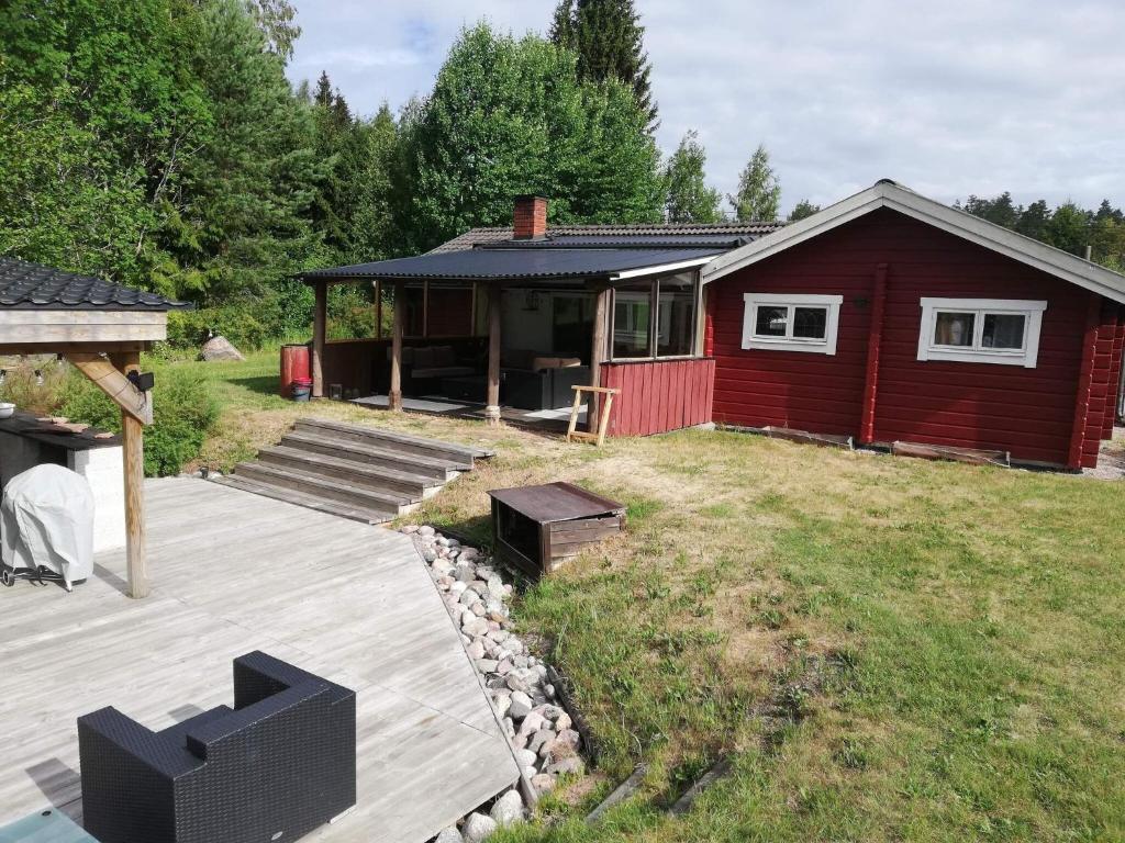 een rood huis met een terras in een tuin bij Holiday home Skutskär in Älvkarleby