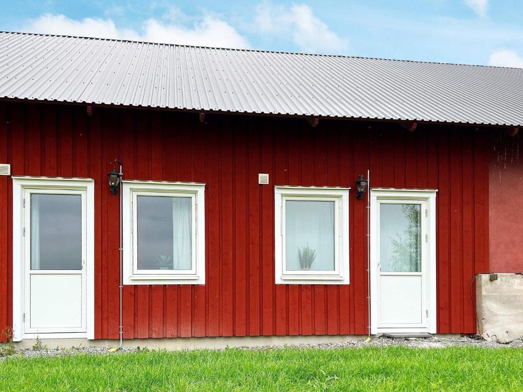 a red barn with three windows and a roof at 5 person holiday home in MUNSö-By Traum in Solsidan