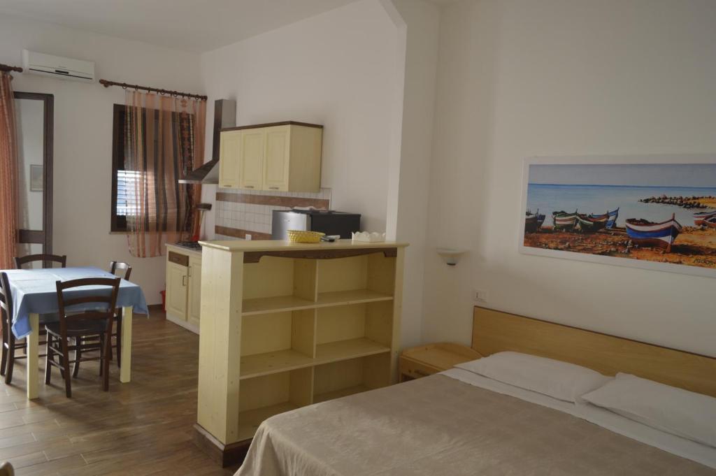 a bedroom with a bed and a table and a table and chairs at Le Anfore Appartamenti in Lampedusa