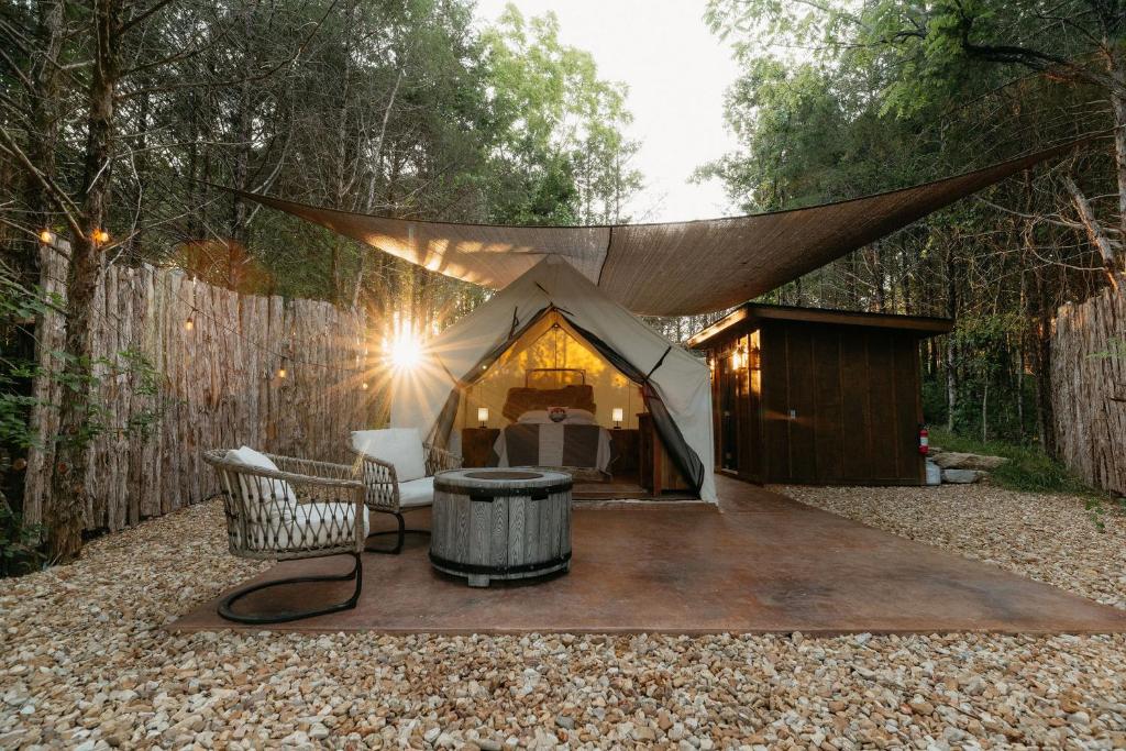 Cozy Unique Glamping on 53 acres - Bedrock Site في برانسون: خيمة مع طاولة وكراسي في ساحة