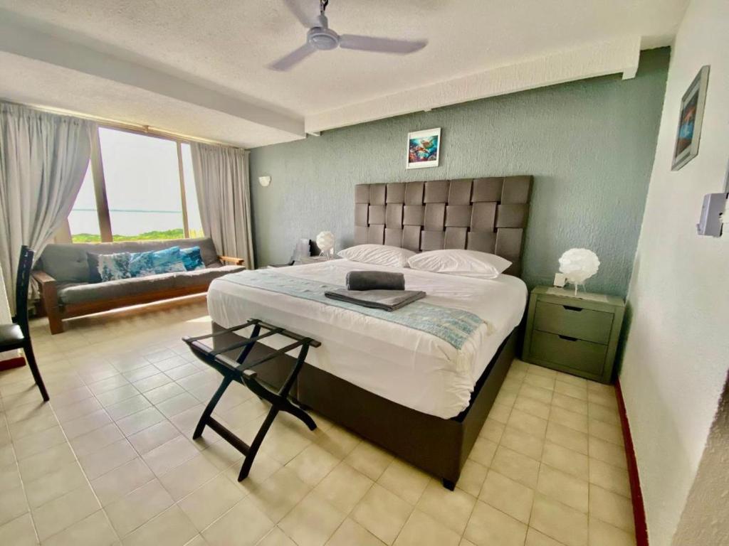een slaapkamer met een groot bed en een bank bij Solymar hermoso apartamento in Cancun