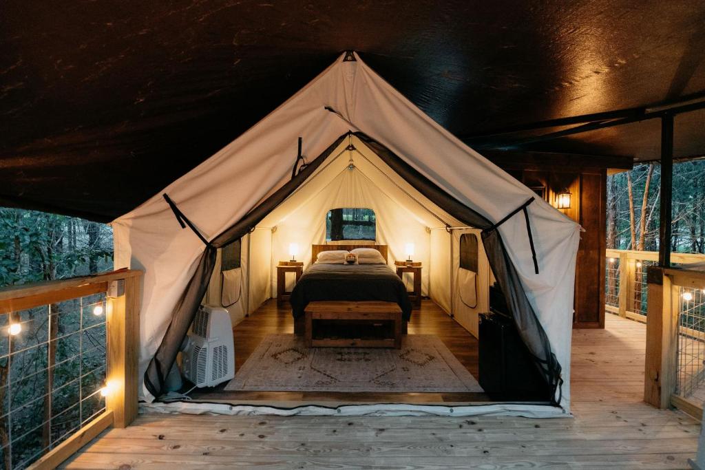 Treehouse Cozy Glamping Site في برانسون: غرفة نوم في خيمة فيها سرير