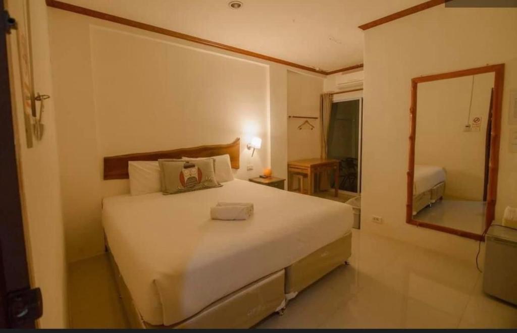 una camera da letto con un grande letto bianco e uno specchio di โรงแรมริเวอร์เลย แกรนด์วิว a Wang Saphung
