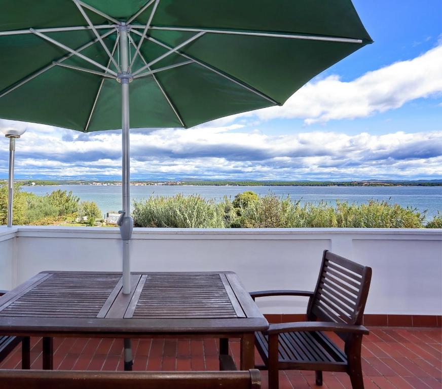 uma mesa de madeira com um guarda-chuva verde numa varanda em Apartment Tkon Rutak em Tkon