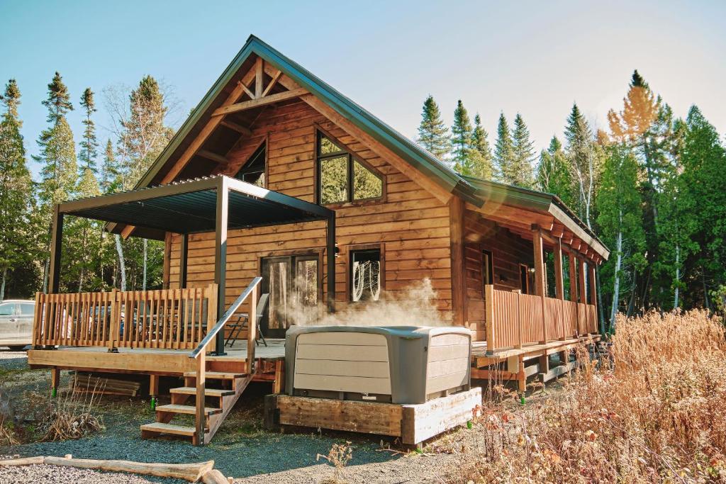 a log cabin with a hot tub in front of it at Le Refuge in Saint-Henri-de-Taillon
