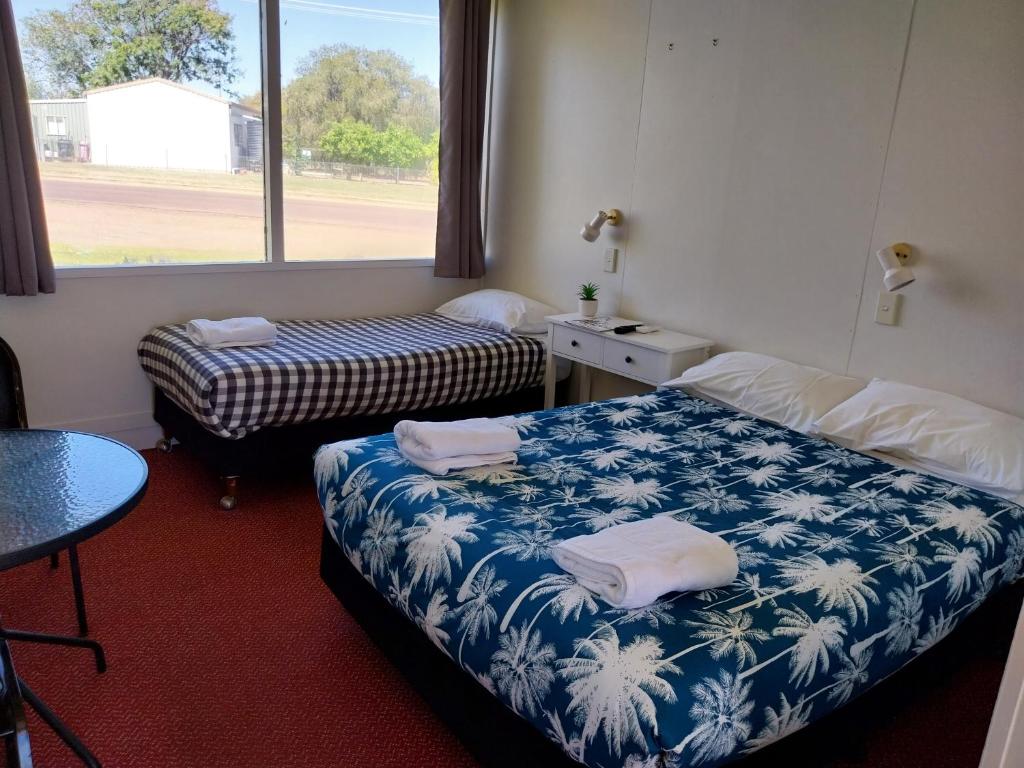 Zimmer mit 2 Betten, einem Tisch und einem Fenster in der Unterkunft Motel Blackall in Blackall