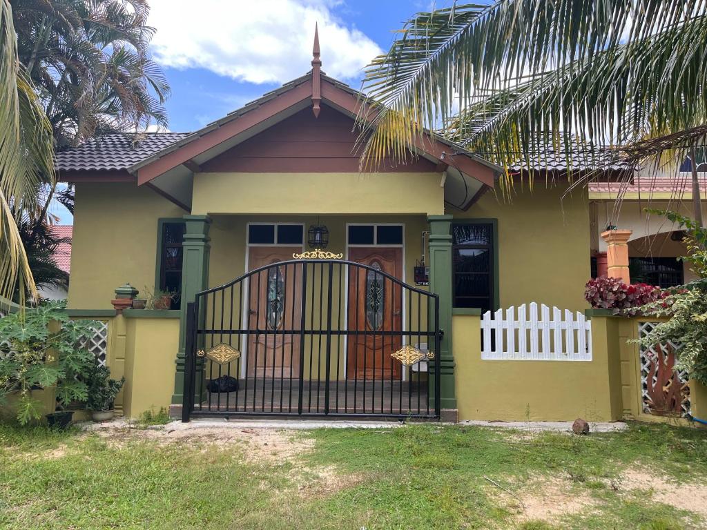 a yellow house with a gate and a fence at HIJRAH FLEKSI HOMESTAY in Kuala Terengganu