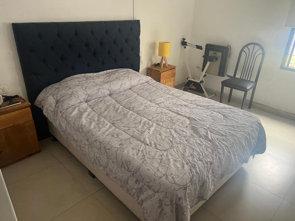 um quarto com uma cama com um edredão cinzento e uma cadeira em bedroom and private bathroom Habitacion y baño privado - en una casa em Córdoba