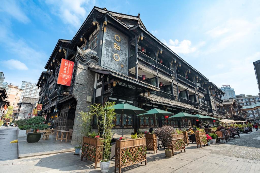 a building with tables and umbrellas on a street at Buddha Zen Hotel in Chengdu