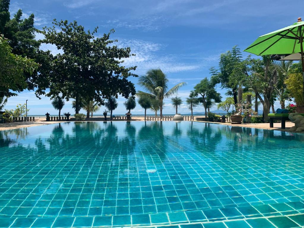 een zwembad met een parasol en palmbomen bij Ban Laem Set - Beachfront Private Luxury Villa in Laem Set Beach