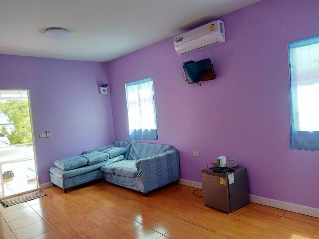 a living room with a couch and a purple wall at คอปเตอร์HOUES in Ban Khlot