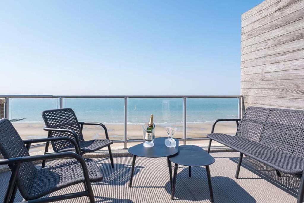 a patio with chairs and a table with a bottle of champagne at Prachtig zeezicht tot 6 personen met garage in Middelkerke