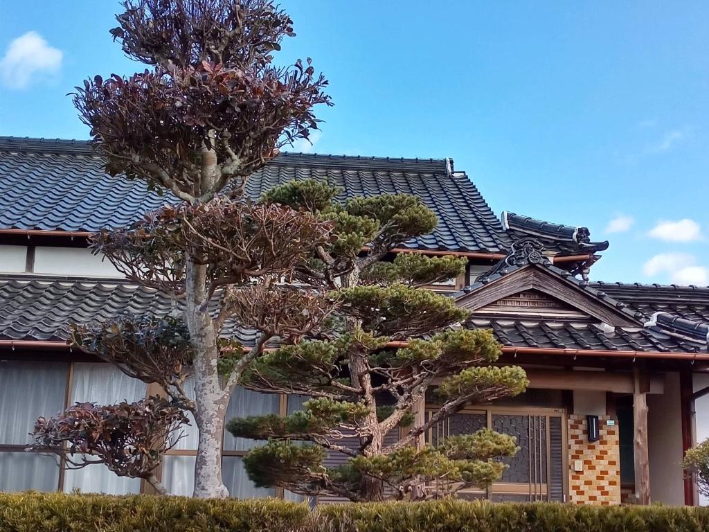 two trees in front of a house at ゲストハウス ふしの庵 in Ogori
