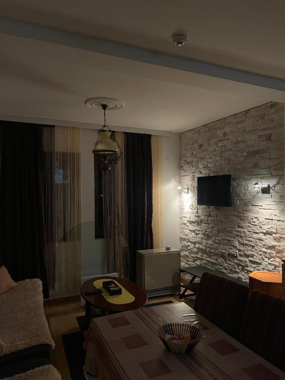 a living room with a couch and a brick wall at Ski apartman - Mujen classic in Kopaonik