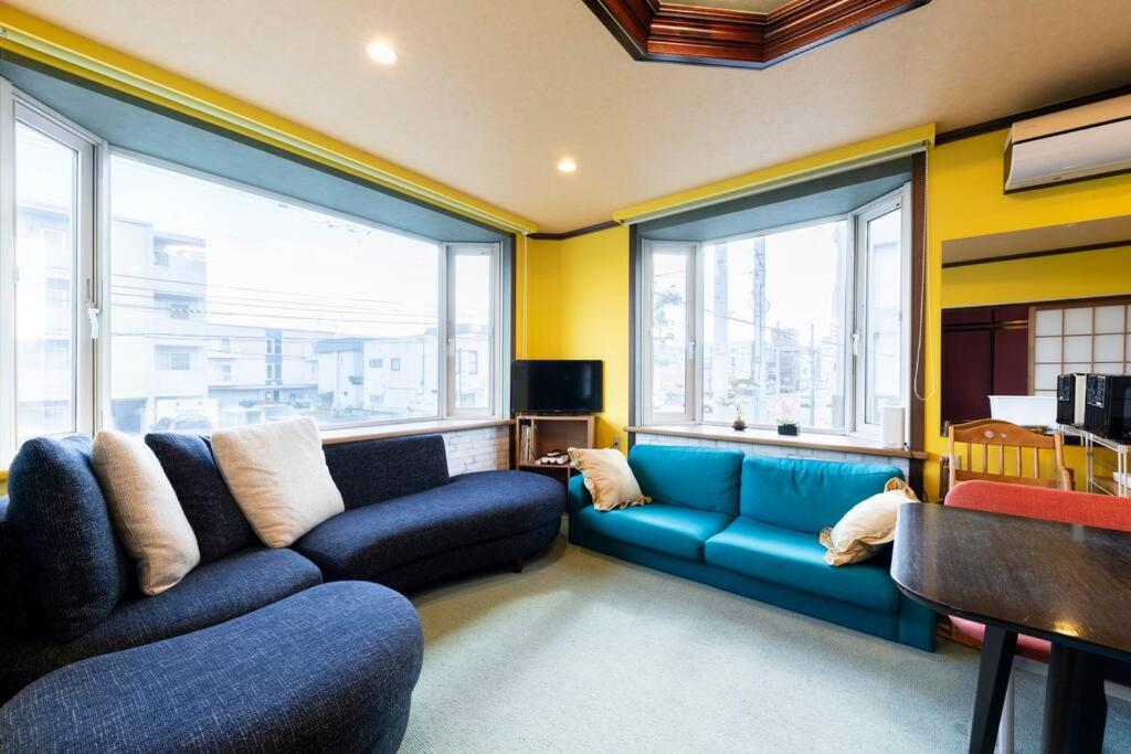 a living room with a blue couch and two windows at Sprinkle inn in Sapporo
