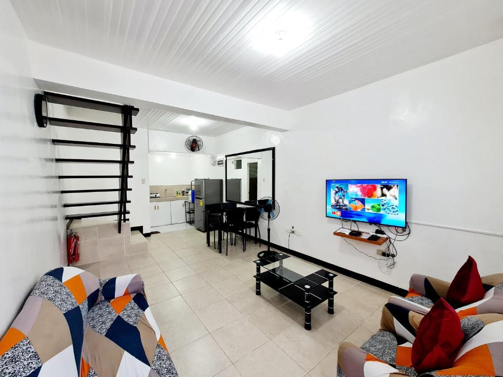 a living room with a couch and a tv on a wall at Calapan Transient Maple L82 in Calapan