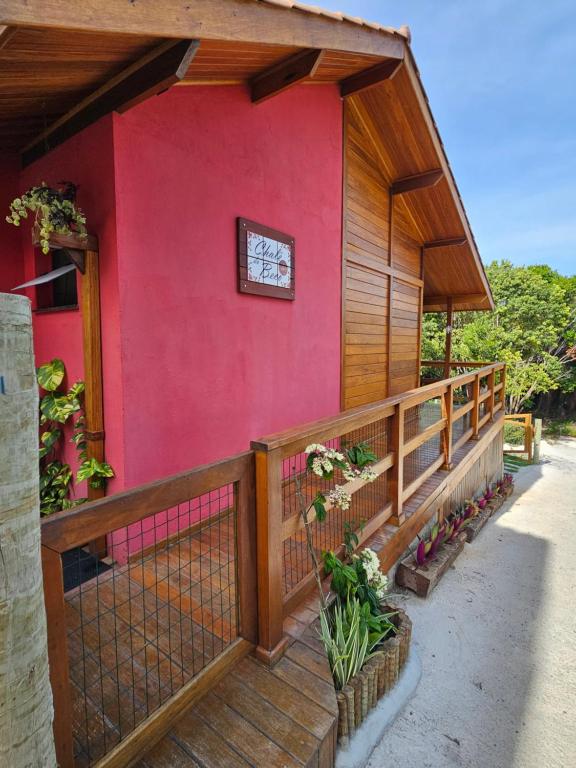 uma casa vermelha com uma varanda de madeira e um relógio em Chalé do Beco - Nova Caraíva em Porto Seguro