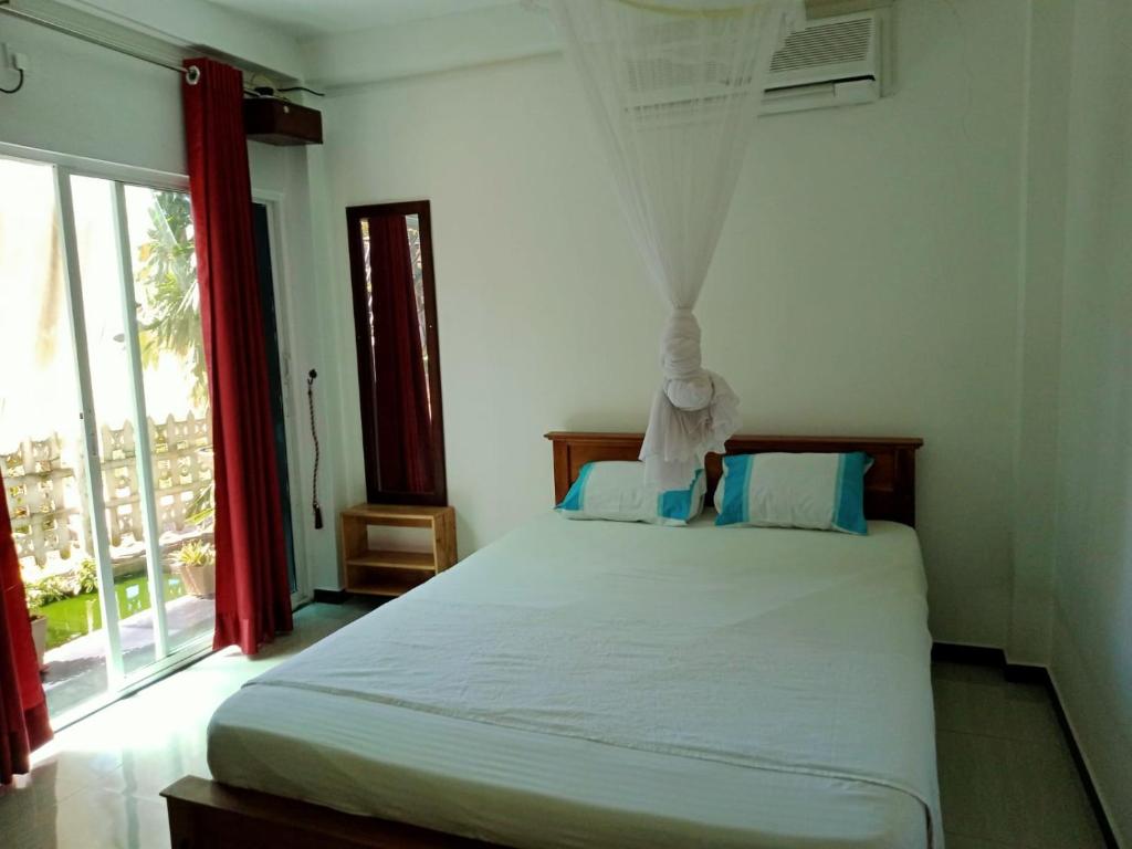- une chambre avec un lit blanc et une fenêtre dans l'établissement Pink Lotus Villa, à Unawatuna