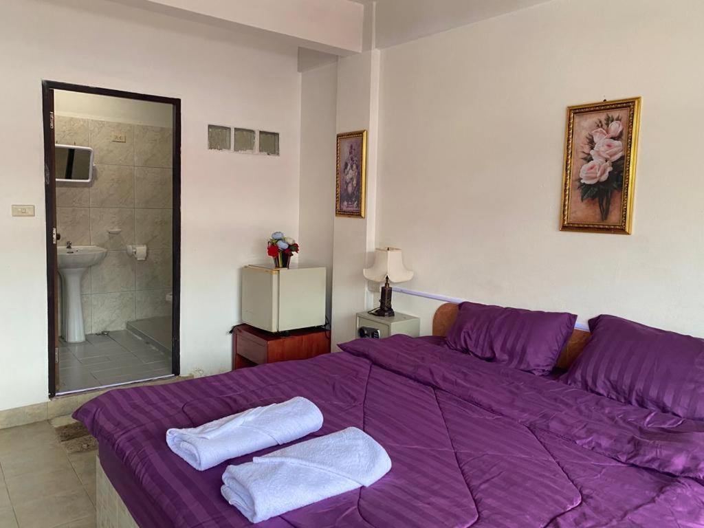 een slaapkamer met een paars bed met handdoeken erop bij Chai Ben guesthouse in Jomtien Beach