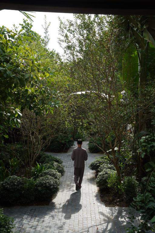 a man walking down a path in a garden at TOKI Retreat Vân Long in Ninh Binh