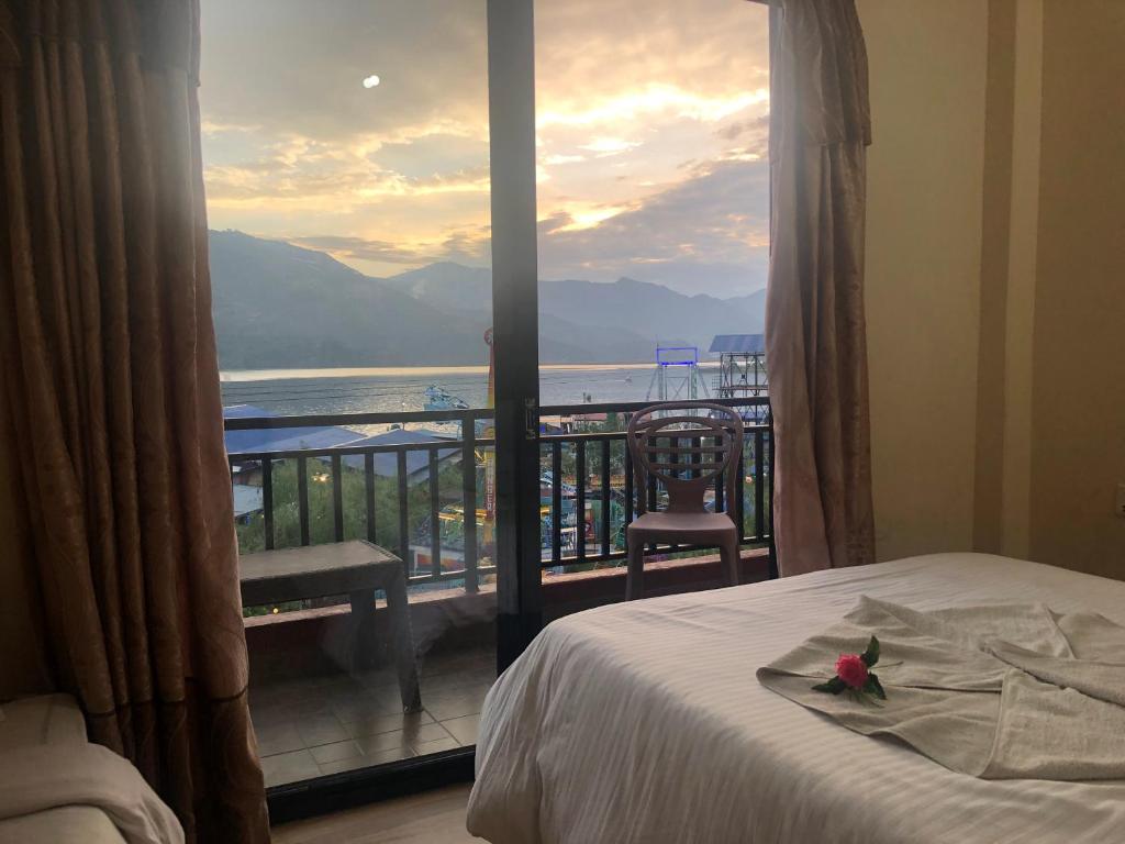 - une chambre avec un lit et un balcon avec vue dans l'établissement Hotel Lake Journey, à Pokhara