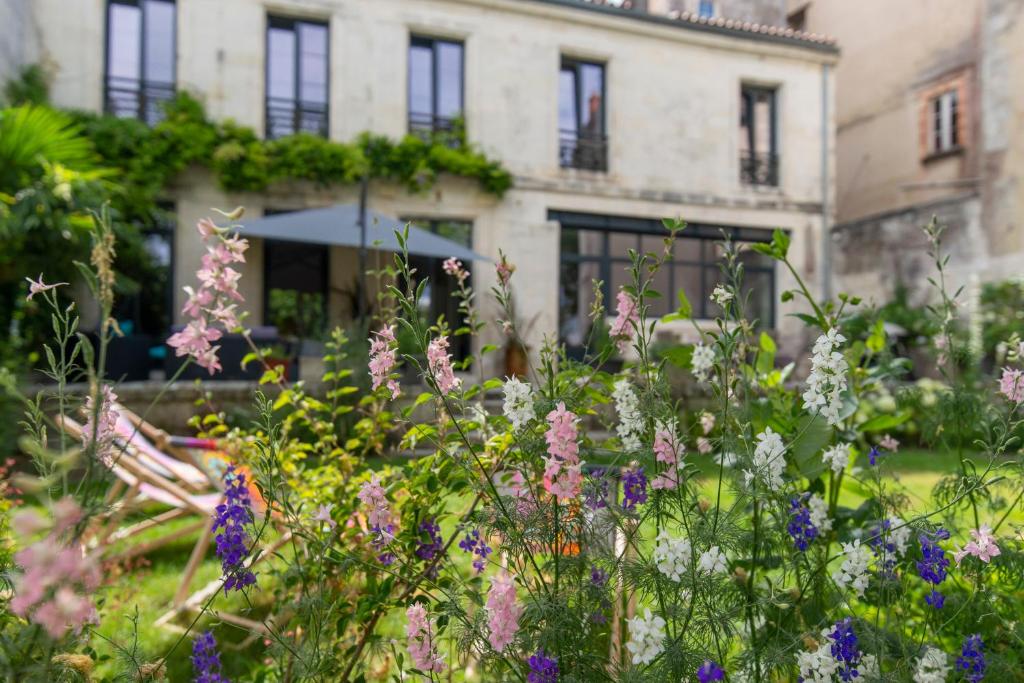 a garden with flowers in front of a building at Escale Rochelaise, chambre privé avec acces toute l'année au SPA chauffée et sauna in La Rochelle