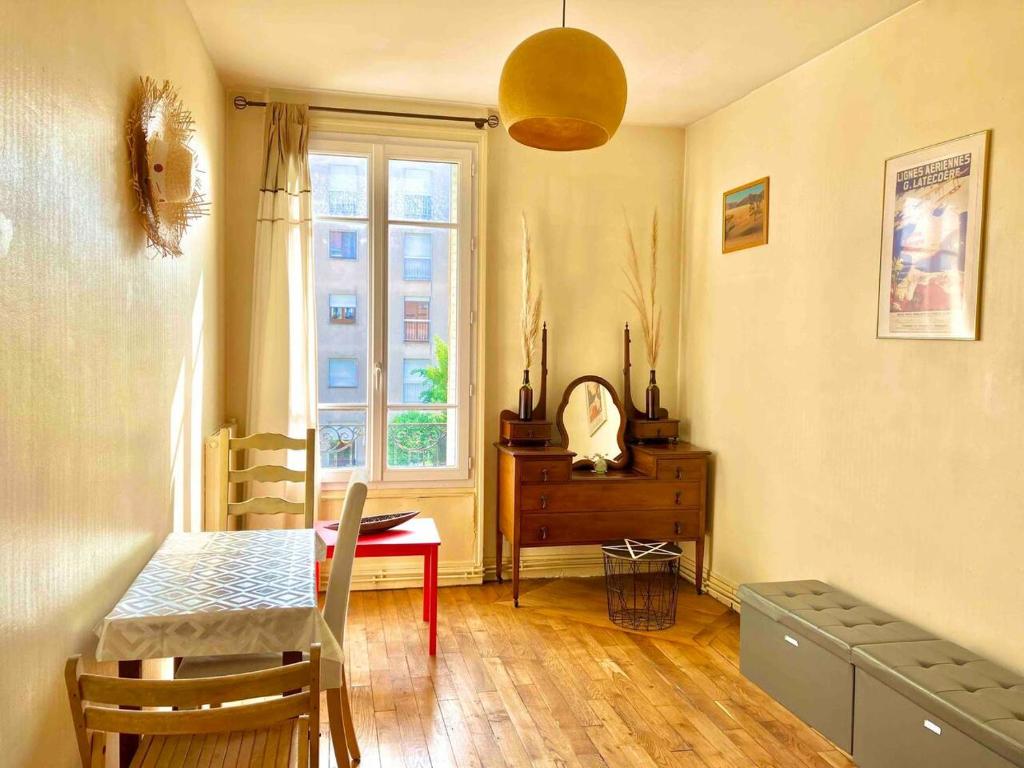 uma sala de jantar com uma mesa e uma janela em Charmant appartement 1930 Centre-ville Nogent-sur-Marne em Nogent-sur-Marne